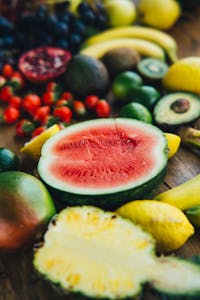 A colorful selection of fresh tropical fruits including watermelon, pineapple, and avocado on a wooden surface.