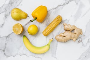 A flat lay of fresh fruits and vegetables on a marble surface, showcasing colorful produce.