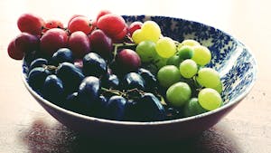 A vibrant bowl of fresh red, green, and black grapes, showcasing healthy eating.