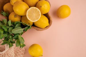 Bright and fresh lemons with mint leaves on a pastel background, perfect for culinary themes.